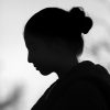 Artistic black and white silhouette of a woman with a hair bun captured in profile view.